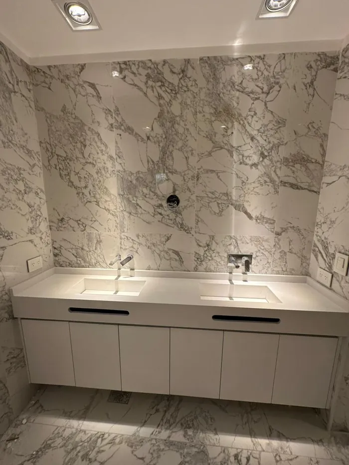 Baño revestido en placas de mármol veteado de piso a techo