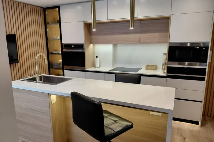 Isla de cocina con mesada clara y frente de listones de madera