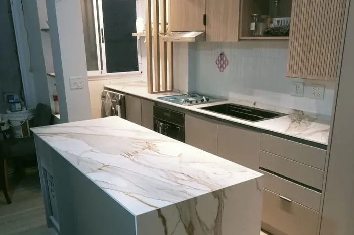 Isla de cocina en calacatta con caída lateral y frente de madera