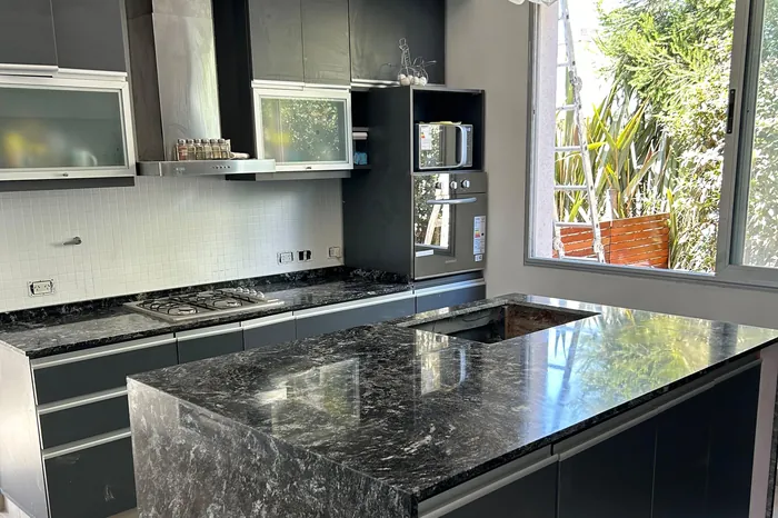 Isla de cocina en granito negro con anafe integrado