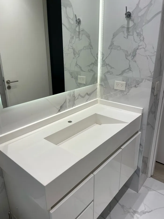 Vanitory de baño con bacha integrada y pared revestida en mármol