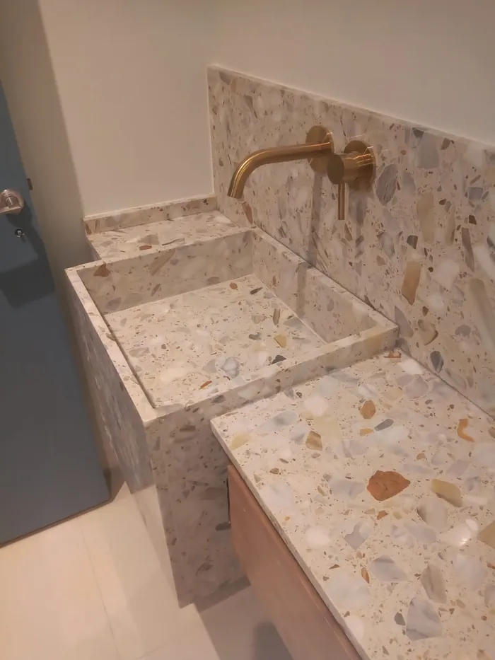 Vanitory de baño en terrazo con grifería dorada de pared