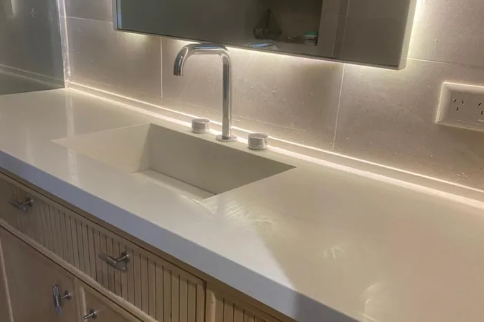 Vanitory de baño en piedra clara con espejo y luz perimetral